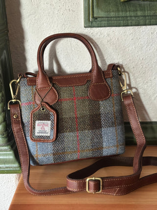 Das Foto zeigt eine Aufnahme der Mini Tote mit Schultergurt. Der Schultergurt wird an zwei D-Ringen an den Seiten der Tasche befestigt. Der Schultergurt lässt sich in seiner Länge mit einem Verschieben rasch verstellen.