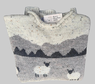 Der Aran Schafpullover ist zusammengelegt. Das Motiv Schafe in Bergen ist gut zu sehen.