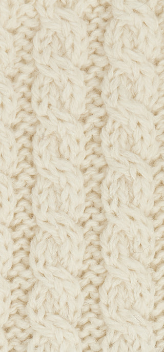 Detailaufnahme des Zopfstrickmusters in weißer Wolle.
