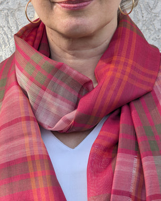 Zu sehen ist ein feiner karierter Merino Schal in den Farben rosa, grün und orange an einem weiblichen Model. 