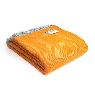 Zu sehen ist eine zusammengelegte klassische Herringbone-Decke aus reiner Schurwolle in den Farben Orange & Grau.