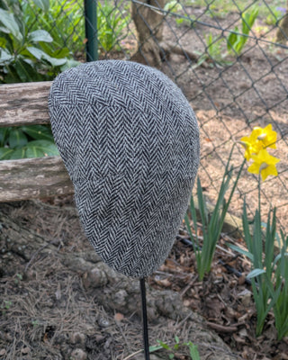 Zu sehen ist eine Schiebemütze aus Harris Tweed in Schwarzweiß