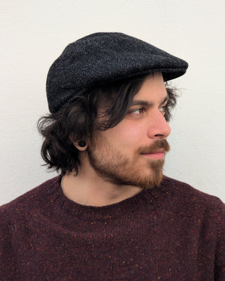Zu sehen ist eine Schiebemütze aus Harris Tweed in Schwarzgrau