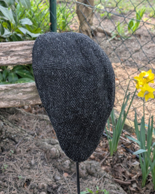 Zu sehen ist eine Schiebemütze aus Harris Tweed in Schwarzgrau