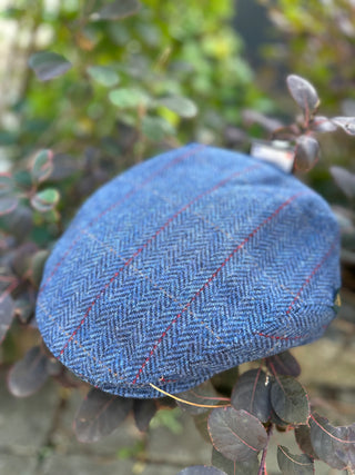 Die Tweed Kappe ist in Dreiviertelansicht zu sehen. Gut erkennbar ist das feine Strukturkaro, das im Fischgrätenmuster drinnen ist.