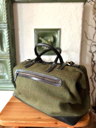 Die Doctor Bag ist in Dreiviertelansicht abgelichtet. Der grüne Wolltweed ist mit einem Musterkaro schön gestaltet. Kombiniert ist die Tasche mit dunkelbraunem Leder. 