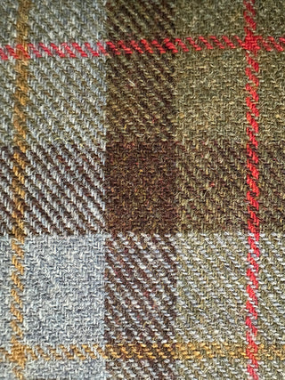 Die Aufnahme zeigt eine Vergrößerung des Harris Tweeds: das Tweedmuster besteht aus blau, grün, braun, in dem rote und gelbe Streifen eingetragen sind.