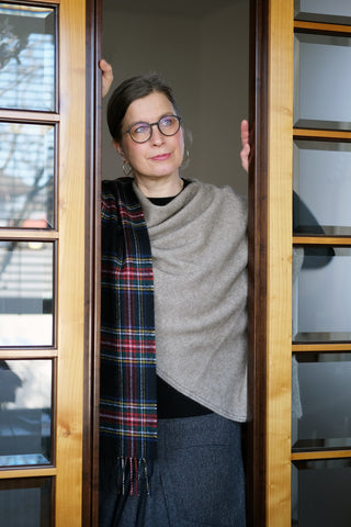 Das beigefarbene Cape ist mit einem Tartan Lammwollschal Black Stewart kombiniert.