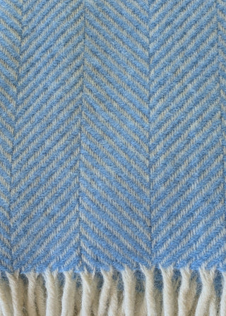 Zu sehen ist eine Detailaufnahme einer klassischen Herringbone-Decke aus reiner Schurwolle in der Farbe Meerblau.