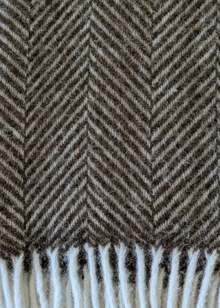 Zu sehen ist eine Detailaufnahme einer klassischen Herringbone-Decke aus reiner Schurwolle in der Farbe Schoko.