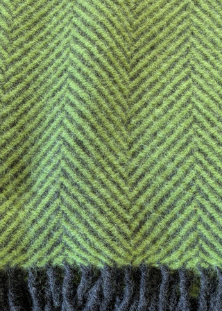 Zu sehen ist eine Detailaufnahme einer klassischen Herringbone-Decke aus reiner Schurwolle in den Farben Zest & Holzkohle.