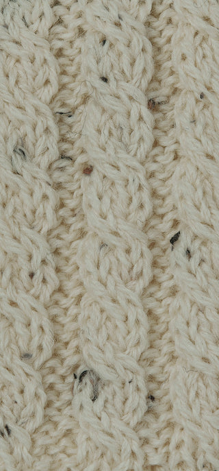 Detailaufnahme des Zopfstricks mit hellbeige Wolle mit Farbtupfern.